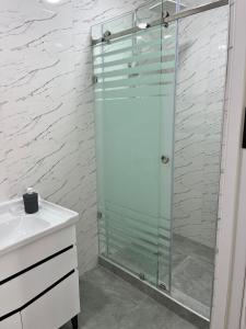 La salle de bains est pourvue d'une douche en verre et d'un lavabo. dans l'établissement Oscar, à Samarcande