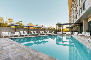 a swimming pool with chairs and a building at AC Hotel by Marriott Scottsdale North in Scottsdale