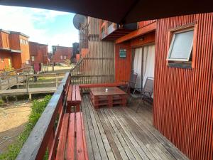 una terraza de madera con bancos y una mesa en un edificio en Condominio Privado a Pasos del Mar, en Pichilemu