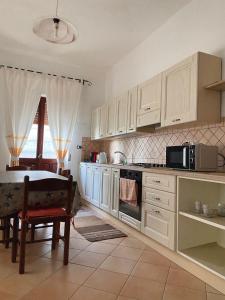 cocina con armarios blancos y mesa con microondas en ASSUMBRA Casa Vacanze, en Santa Maria Navarrese