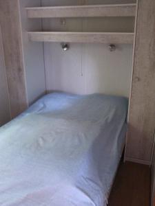 een bed in een kleine kamer met een wit laken bij Stacaravanverhuur Kroon chalet B-10 in Workum