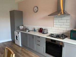 a kitchen with a stove and a sink and a microwave at 5 minutes from Loch Lomond - Recently Renovated in 2023 Ground Floor 1-Bed Flat in Bonhill
