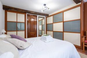 a bedroom with a white bed with large windows at Céntrico y tranquilo apartamento in Bermeo