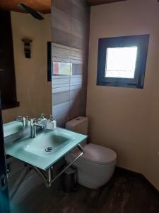uma casa de banho com um lavatório, um WC e uma janela. em la casa de las cabilas em Cuevas del Valle