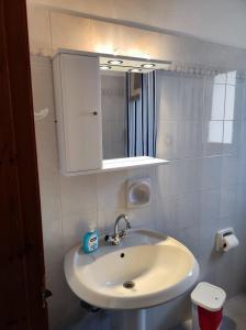 een badkamer met een witte wastafel en een spiegel bij Blue Sea Studios in Arkasa