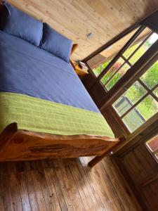 Cama en medio de una habitación con ventanas en Villa Feliz Ecolodge, en Monterrey