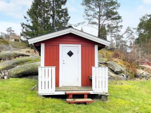 een rood-witte schuur in een grasveld bij Holiday home HAKENÄSET IV in Balkeröd