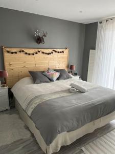 Schlafzimmer mit einem großen Bett mit einem Kopfteil aus Holz in der Unterkunft Maison avec piscine chauffée in Peigny