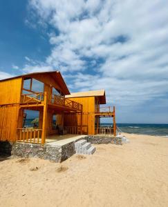 a wooden building on a beach with the ocean at Full Moon Camp Sinai in Nuweiba