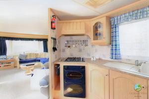 a kitchen with a blue stove top oven in a caravan at Orchard View Retreat - Dog friendly, enclosed private garden with weather dependant hot tub - Not on a holiday park in Little Clacton