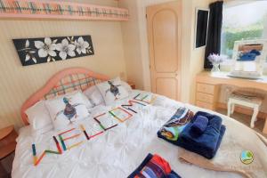 a bedroom with a white bed with colorful pillows at Orchard View Retreat - Dog friendly, enclosed private garden with weather dependant hot tub - Not on a holiday park in Little Clacton