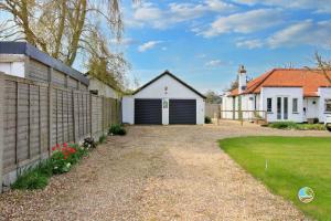 a house with a garage and a fence at Orchard View Retreat - Dog friendly, enclosed private garden with weather dependant hot tub - Not on a holiday park in Little Clacton