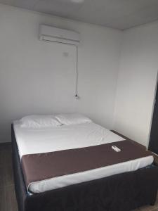 Bett in einem Zimmer mit einer weißen Wand in der Unterkunft Cabañas alma llanera in Villavicencio