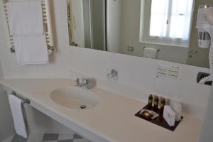 a white bathroom with a sink and a mirror at Albergo Alla Posta in Trieste