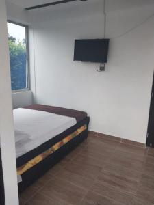 Schlafzimmer mit einem Bett und einem Flachbild-TV in der Unterkunft Cabañas alma llanera in Villavicencio