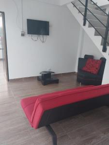 ein Wohnzimmer mit einem roten Sofa und einem TV in der Unterkunft Cabañas alma llanera in Villavicencio