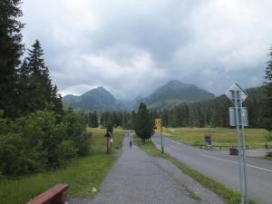une personne se promenant sur une route avec des montagnes en arrière-plan dans l'établissement Byt Zuzana, à Štrbské Pleso