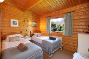 a bedroom with two beds in a log cabin at Birchlea in Kippford