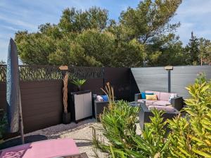 L'Instant Mer - Bord de Mer - Studio avec grand jardin à La Capte في هييريس: حديقة خلفية بها سياج وكرسي وأريكة