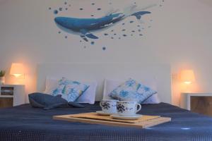 een bed met twee kopjes en een walvis aan de muur bij Calilla Home-appartamento Scirocco in Grado