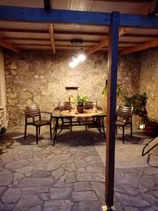 een patio met een tafel en stoelen en een stenen muur bij RafaelHouse in Chania