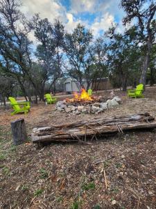 a fire pit in a park with chairs and trees at River Dreams Cabins & Glamping in Concan