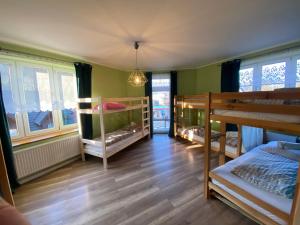 a room with two bunk beds and a hallway with windows at Hostel 1902 in Zakopane