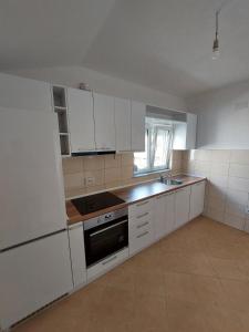 an empty kitchen with white cabinets and a sink at Indijano Apartment in Ohrid