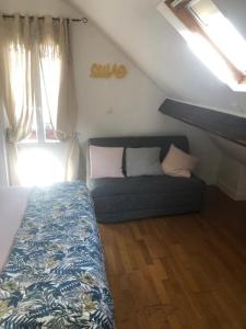 een slaapkamer met een bed en een bank op zolder bij Grand studio aéré entre sol in Montreuil