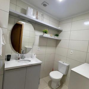 a bathroom with a toilet and a sink and a mirror at Apartamento aconchegante novo in Bento Gonçalves