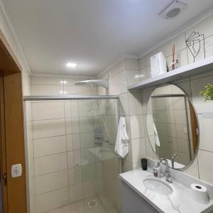 a bathroom with a shower and a sink and a mirror at Apartamento aconchegante novo in Bento Gonçalves