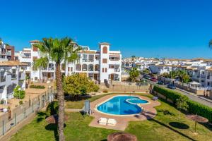 an apartment with a swimming pool and palm trees at CB Living - Scenic duplex with pool in Punta Prima in Orihuela Costa