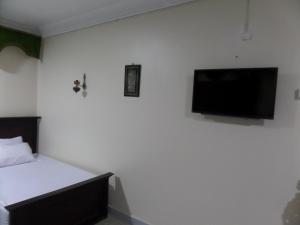 a bedroom with a bed and a flat screen tv on the wall at Grand Museum Guest House in Kafr Abū ʼumaydah