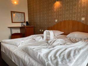 a large white bed with a person laying on it at Family hotel Deykin in Sunny Beach