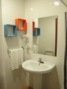 a bathroom with a sink and a mirror and towels at Apartamentos Turísticos Cancelas by Bossh Hotels in Santiago de Compostela
