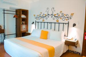 ein Schlafzimmer mit einem Bett mit orangefarbenen und weißen Kissen in der Unterkunft Hotel Oaxaca Real in Oaxaca de Juárez + 25 Fotos