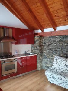 cocina con armarios rojos y pared de piedra en Roccetta Fiorita, en Pettenasco