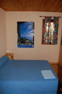 Un dormitorio con una cama azul y un cartel en la pared en Gites Chalets de Grosseto-Prugna en Grosseto-Prugna