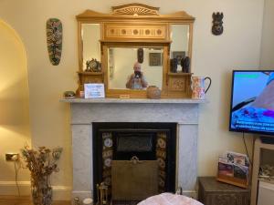 a living room with a fireplace with a mirror and a tv at Mountroyal Victorian Self Catering Apartment 2 in Belfast