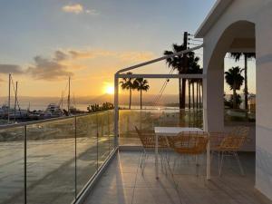 een tafel en stoelen op een balkon met uitzicht op de zonsondergang bij Latchi Marina View in Polis Chrysochous