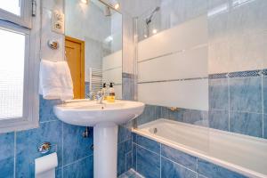 La salle de bains bleue et blanche est pourvue d'un lavabo et d'une baignoire. dans l'établissement CASACAFÉ Madrid Pozuelo Estación Private Rooms, à Pozuelo de Alarcón