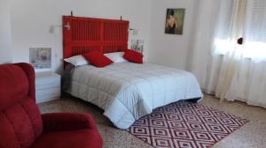 sypialnia z łóżkiem z czerwonym zagłówkiem i krzesłem w obiekcie L' acero rosso w mieście Miglianico