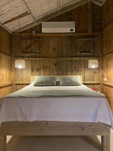Schlafzimmer mit einem großen weißen Bett und Holzwänden in der Unterkunft Cabana Cachandó in Corumbau