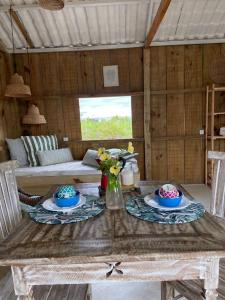 een houten tafel met twee borden en bloemen erop bij Cabana Cachandó in Corumbau