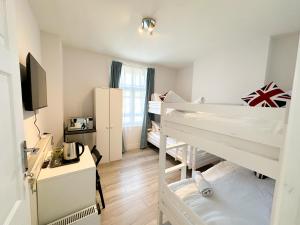 a dorm room with two bunk beds and a desk at Pink Door Guesthouse in London