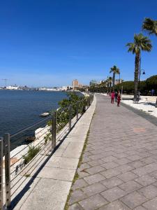 a sidewalk next to the water with palm trees at B&B SU SICCU in Cagliari