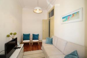 een woonkamer met een witte bank en blauwe kussens bij Casa 11 Cravos in Figueira da Foz