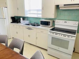 Falls House Downtown Niagara Falls Canada في شلالات نياجارا: مطبخ مع أجهزة بيضاء وطاولة مع كراسي