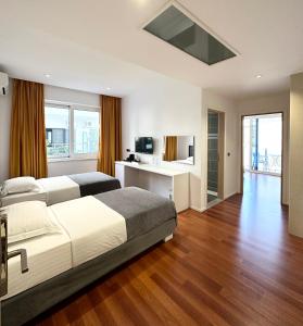 Schlafzimmer mit einem Bett und einem Schreibtisch mit einem TV in der Unterkunft 3B Suites Boutique Hotel in Sarandë
