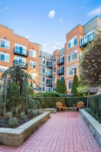 a brick walkway with two benches in front of buildings at Corner Unit in the middle of it all - 99 Walkscore in Seattle